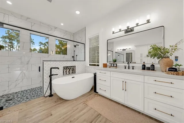 a spacious bathroom with a double vanity sink a mirror a bathtub and a shower