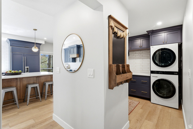 7935 Mustang Loop Road Park City, UT 84098 - Photo 28 of 60 Utility area featuring stacked appliances, dark cabinetry with gold-tone hardware, and subway tile backsplash