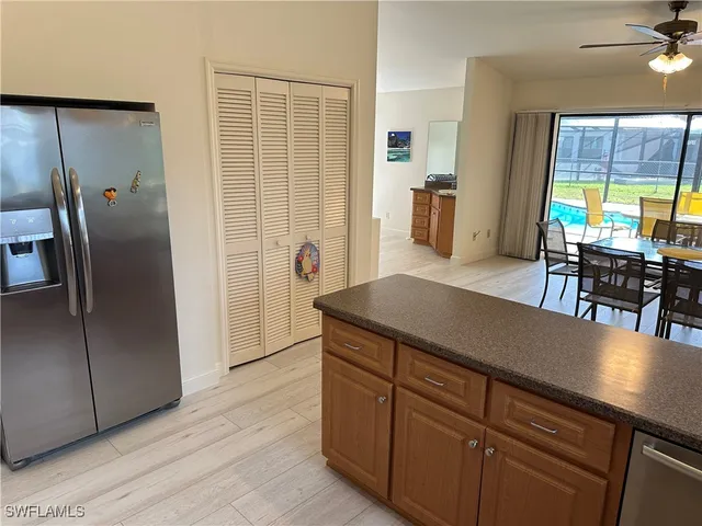 a kitchen with stainless steel appliances granite countertop a refrigerator a stove and a dining table with wooden floor
