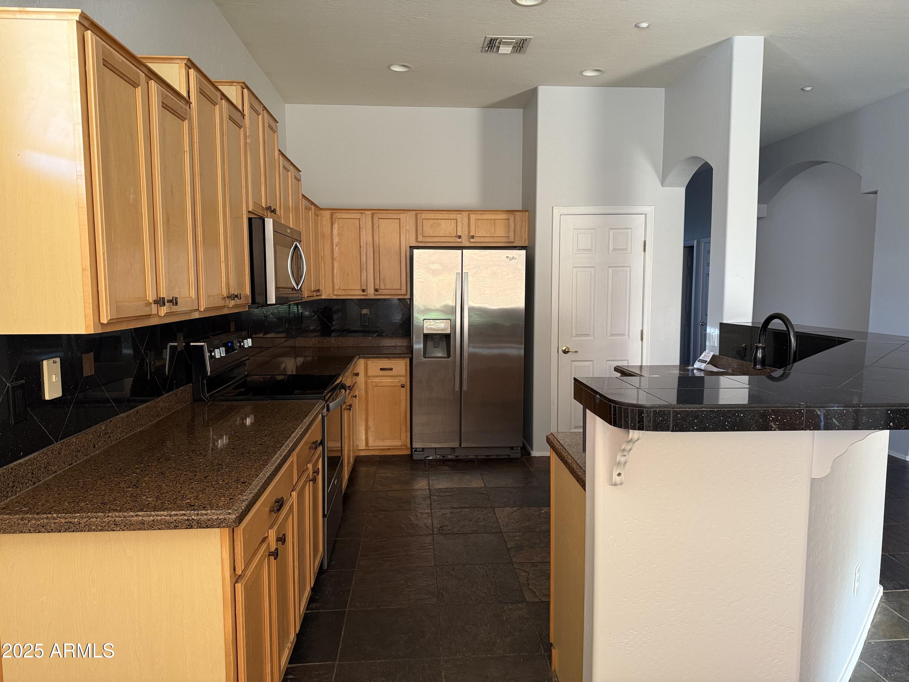 10453 East Pine Valley Drive Scottsdale, AZ 85255 - Photo 11 of 35 a kitchen with stainless steel appliances granite countertop a sink a stove and a refrigerator