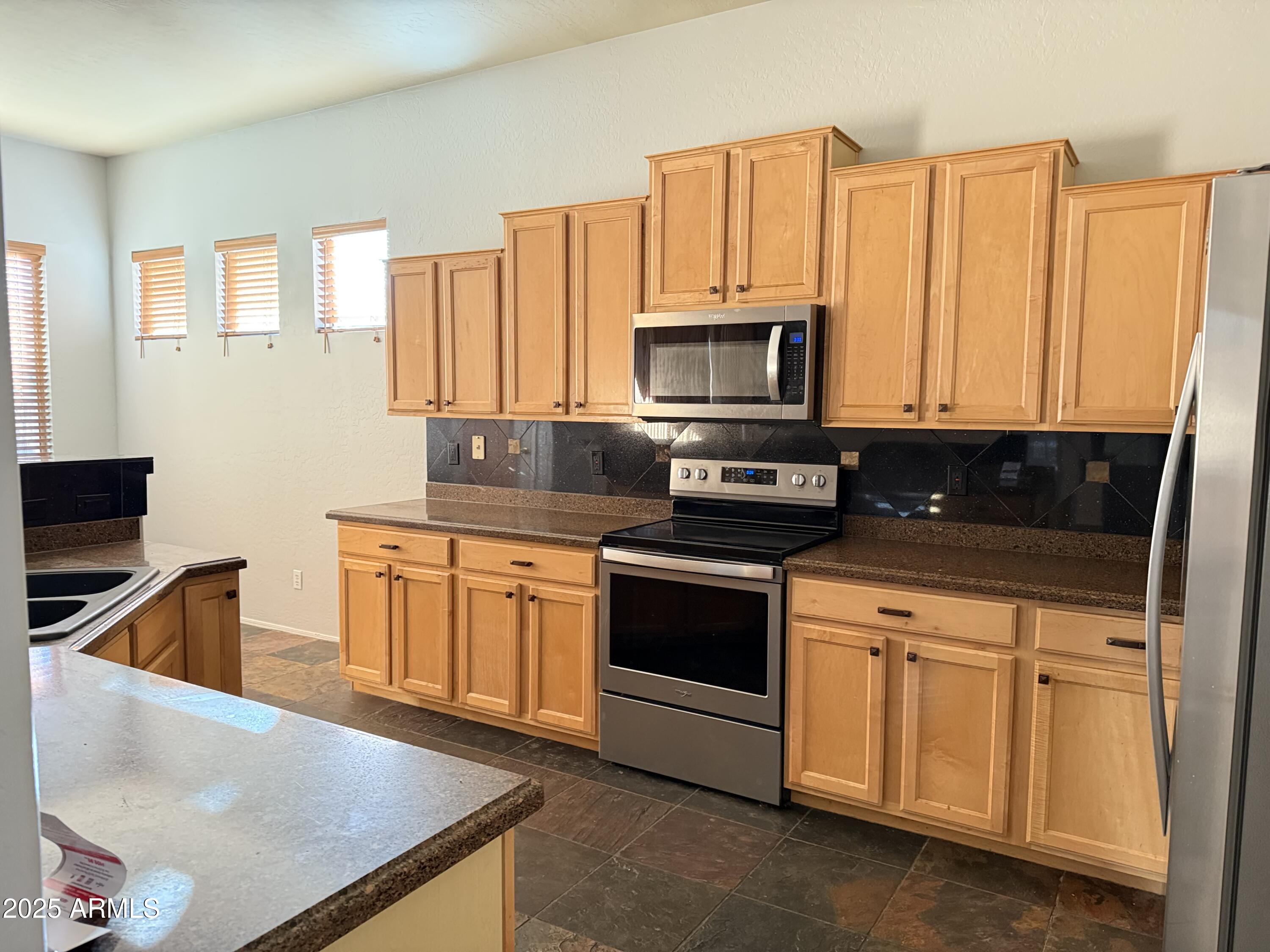 10453 East Pine Valley Drive Scottsdale, AZ 85255 - Photo 13 of 35 a kitchen with stainless steel appliances granite countertop a stove a microwave and a sink