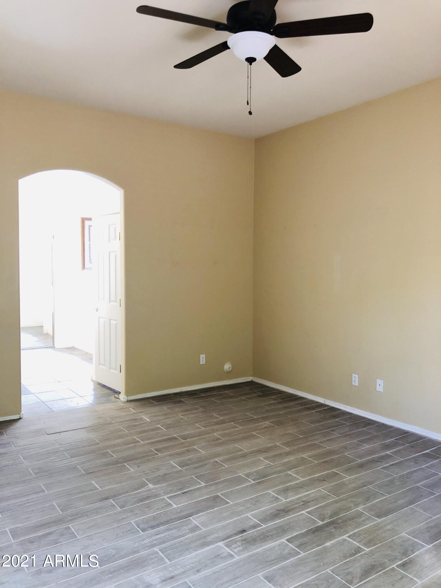 10453 East Pine Valley Drive Scottsdale, AZ 85255 - Photo 15 of 35 an empty room with a ceiling fan and wooden floor