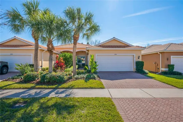 a front view of a house with a garden and palm trees
