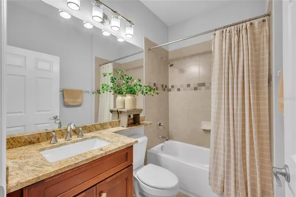 a bathroom with a granite countertop sink a toilet a mirror and shower