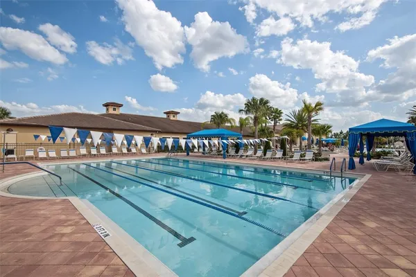 a blue swimming pool with a table and chairs under an umbrella