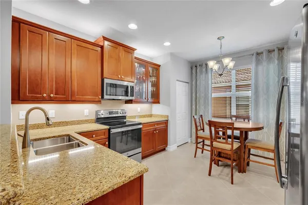 a kitchen with stainless steel appliances granite countertop a stove top oven a sink dishwasher a dining table and chairs with wooden floor