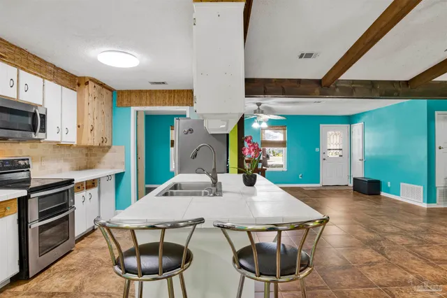 a kitchen with stainless steel appliances a dining table chairs and a refrigerator