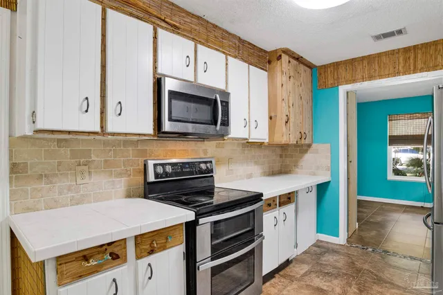 a kitchen with stainless steel appliances a stove microwave and sink