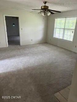 an empty room with windows and fan