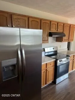 a kitchen with stainless steel appliances granite countertop a refrigerator a stove and a sink
