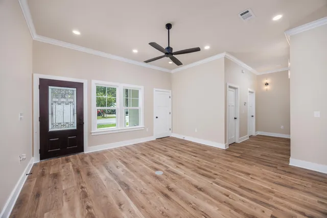 a view of empty room with wooden floor and fan