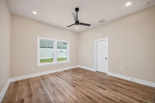 a view of an empty room with window and wooden floor