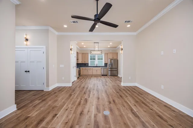 a view of a big room with wooden floor a ceiling fan and windows