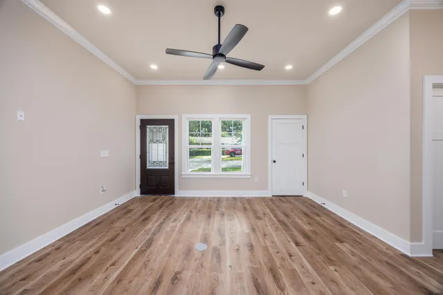 a view of an empty room with wooden floor and a window