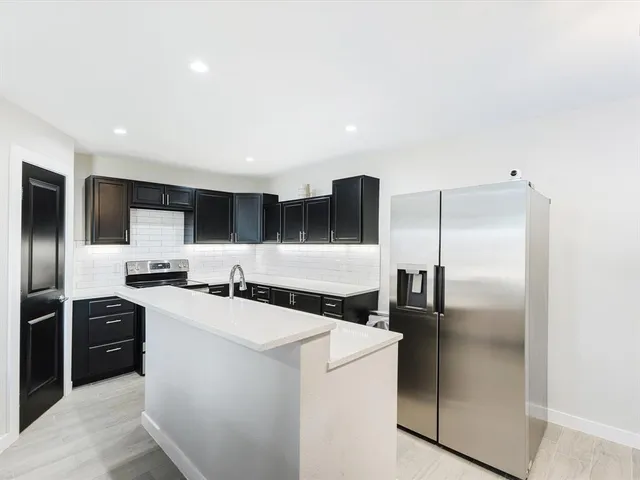 a kitchen with stainless steel appliances granite countertop a refrigerator a stove and a sink