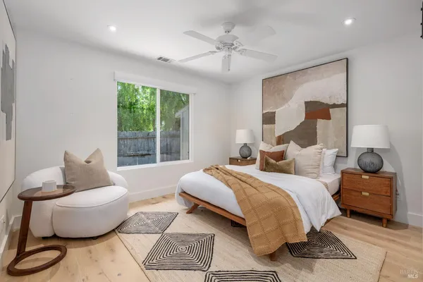 a bedroom with a bed couches chair and a large window