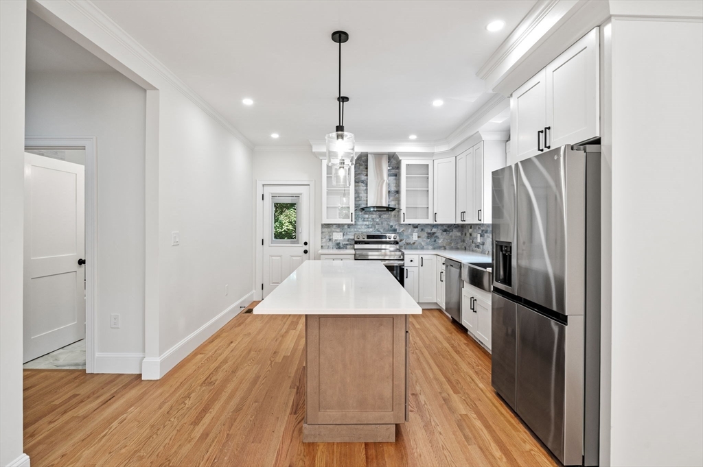 8 Cushing Street, Unit 1 Salem, MA 01970 - Photo 4 of 35 a kitchen with granite countertop a refrigerator a sink dishwasher a stove and white cabinets with wooden floor