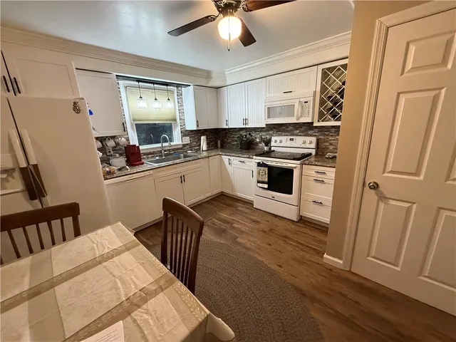 a kitchen with stainless steel appliances a stove a sink dishwasher a refrigerator white cabinets and wooden floor