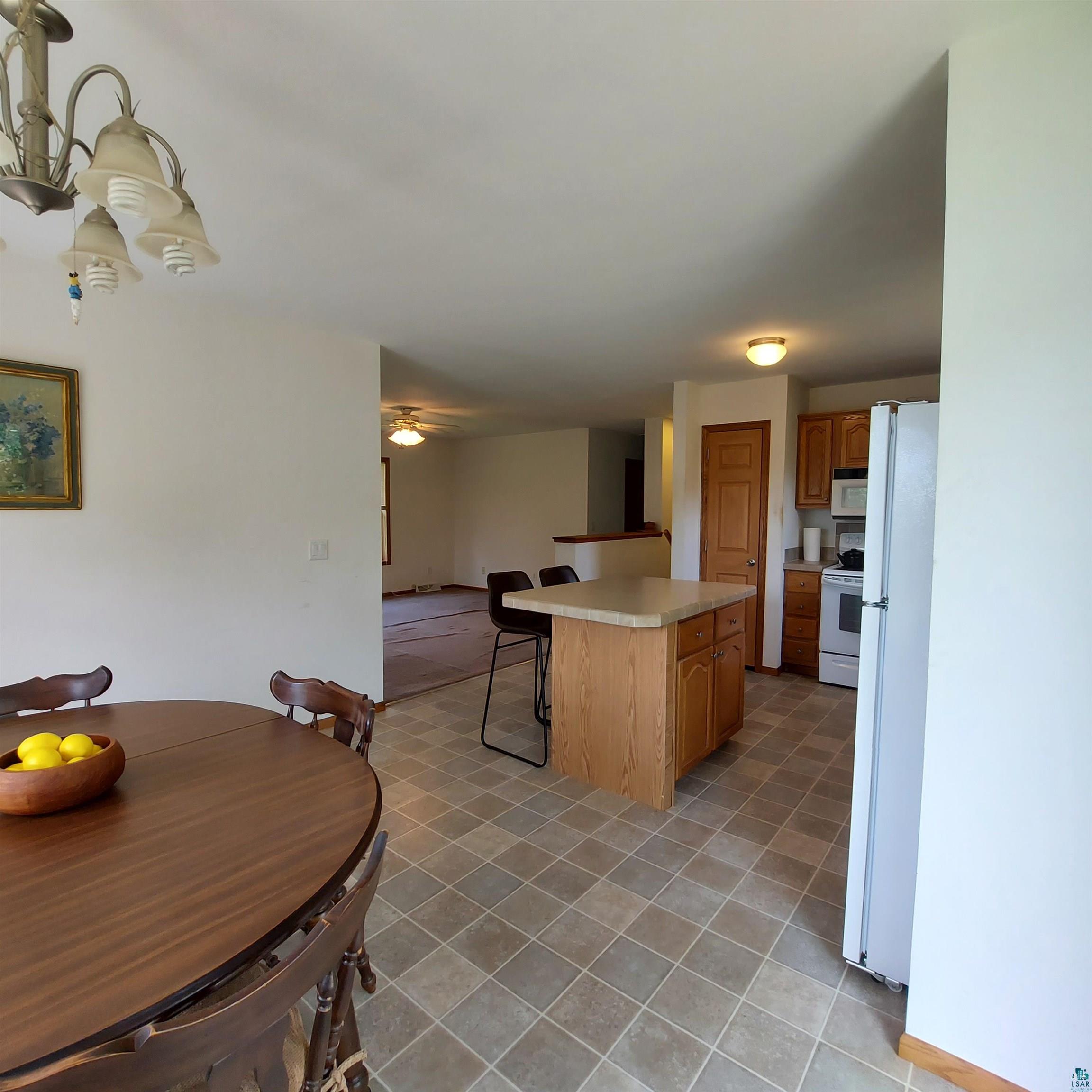 6563 Seville Road Saginaw, MN 55779 - Photo 12 of 28 Kitchen featuring light tile patterned flooring, a breakfast bar, white appliances, a kitchen island, and ceiling fan