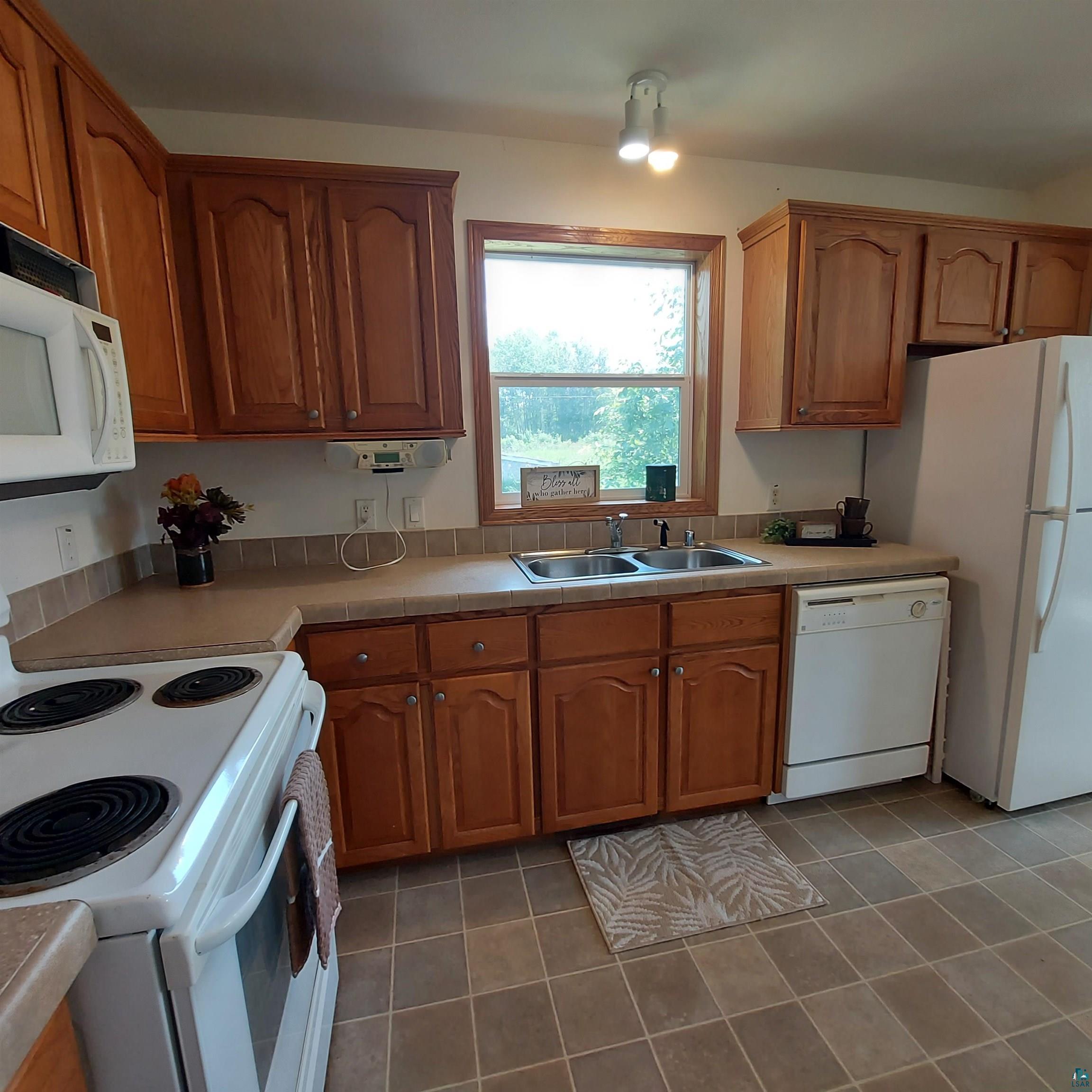6563 Seville Road Saginaw, MN 55779 - Photo 14 of 28 Kitchen with tile patterned flooring, white appliances, and sink