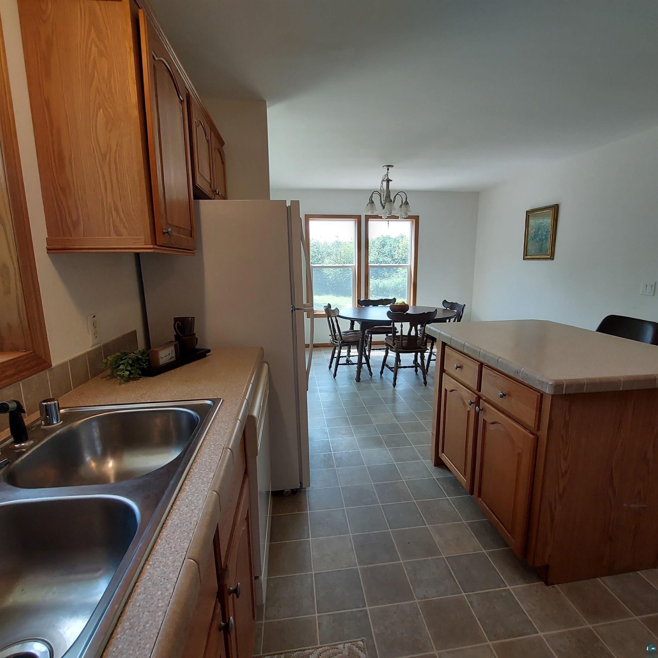 6563 Seville Road Saginaw, MN 55779 - Photo 15 of 28 Kitchen with sink, dark tile patterned floors, and an inviting chandelier