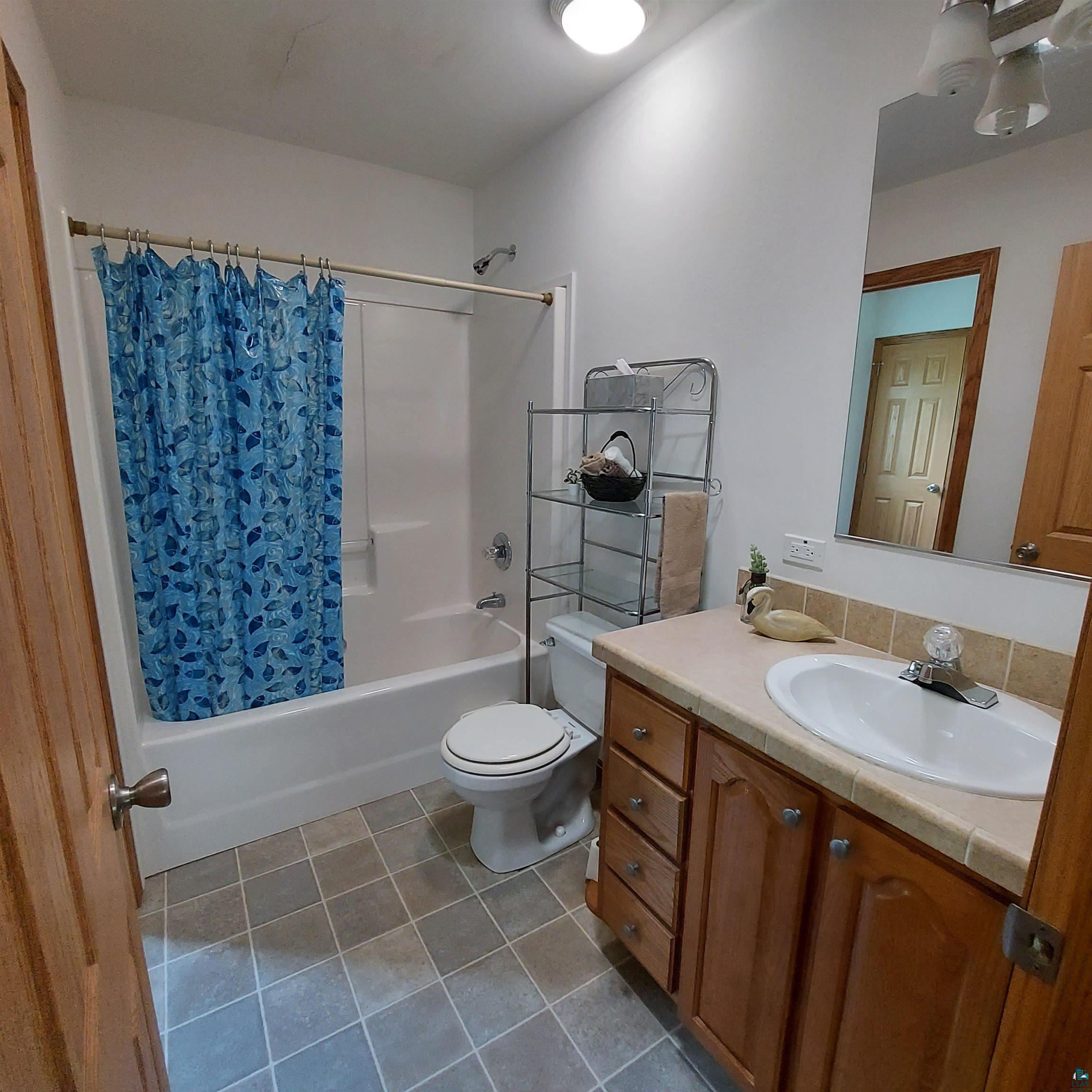 6563 Seville Road Saginaw, MN 55779 - Photo 17 of 28 Full bathroom featuring tile patterned flooring, shower / bath combo, toilet, and vanity
