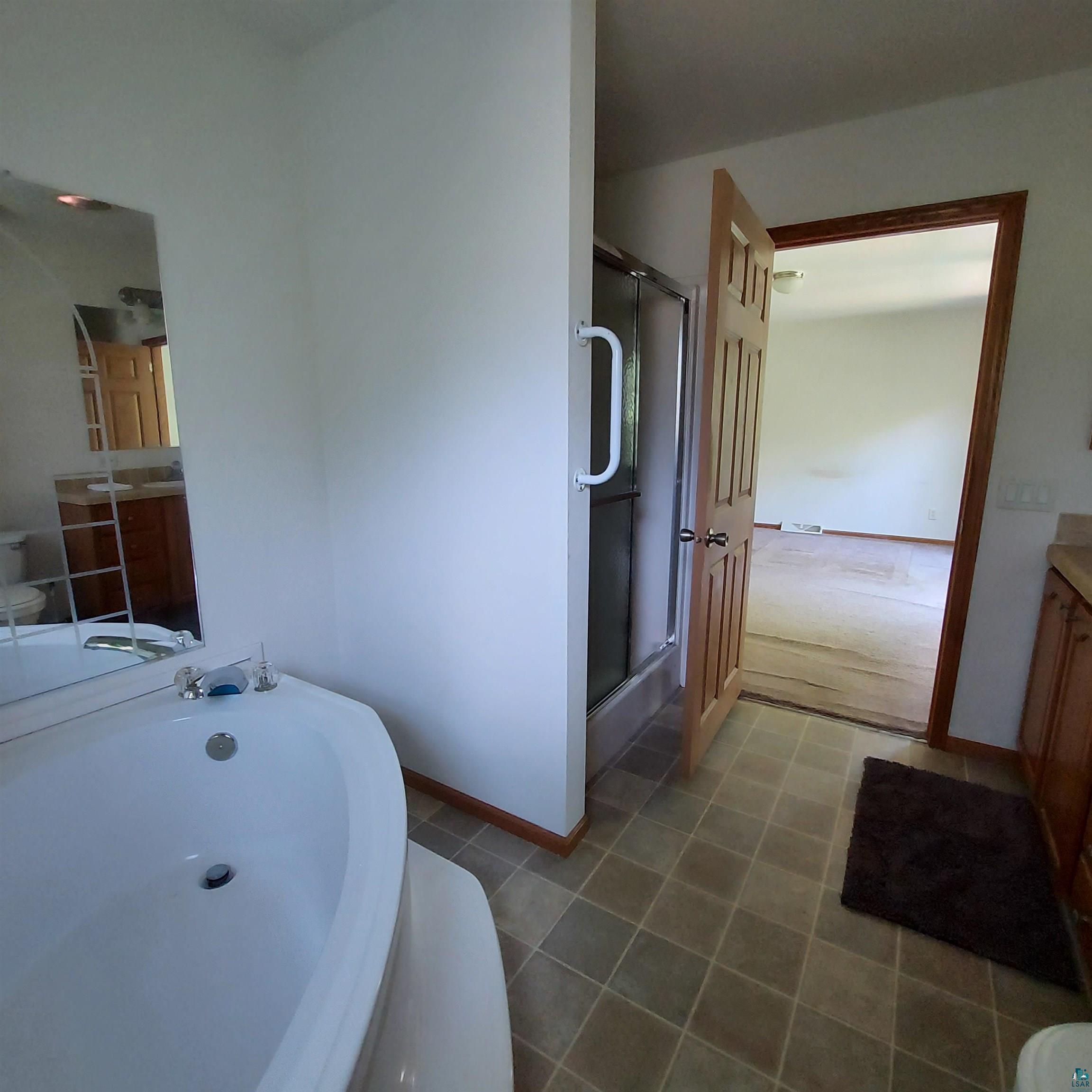 6563 Seville Road Saginaw, MN 55779 - Photo 26 of 28 Full bathroom featuring vanity, independent shower and bath, toilet, and tile patterned floors