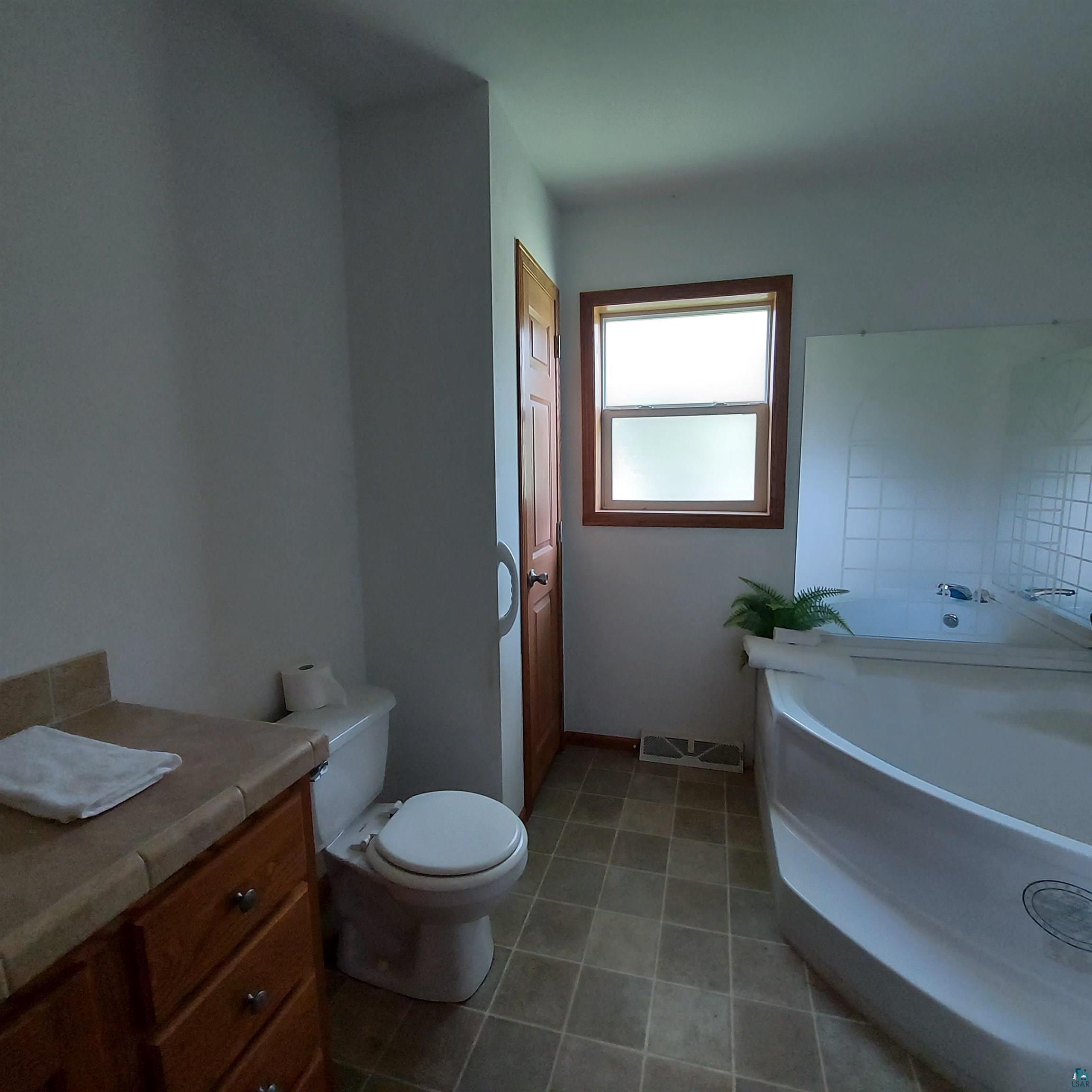6563 Seville Road Saginaw, MN 55779 - Photo 28 of 28 Bathroom with vanity, tile patterned flooring, a bath, and toilet