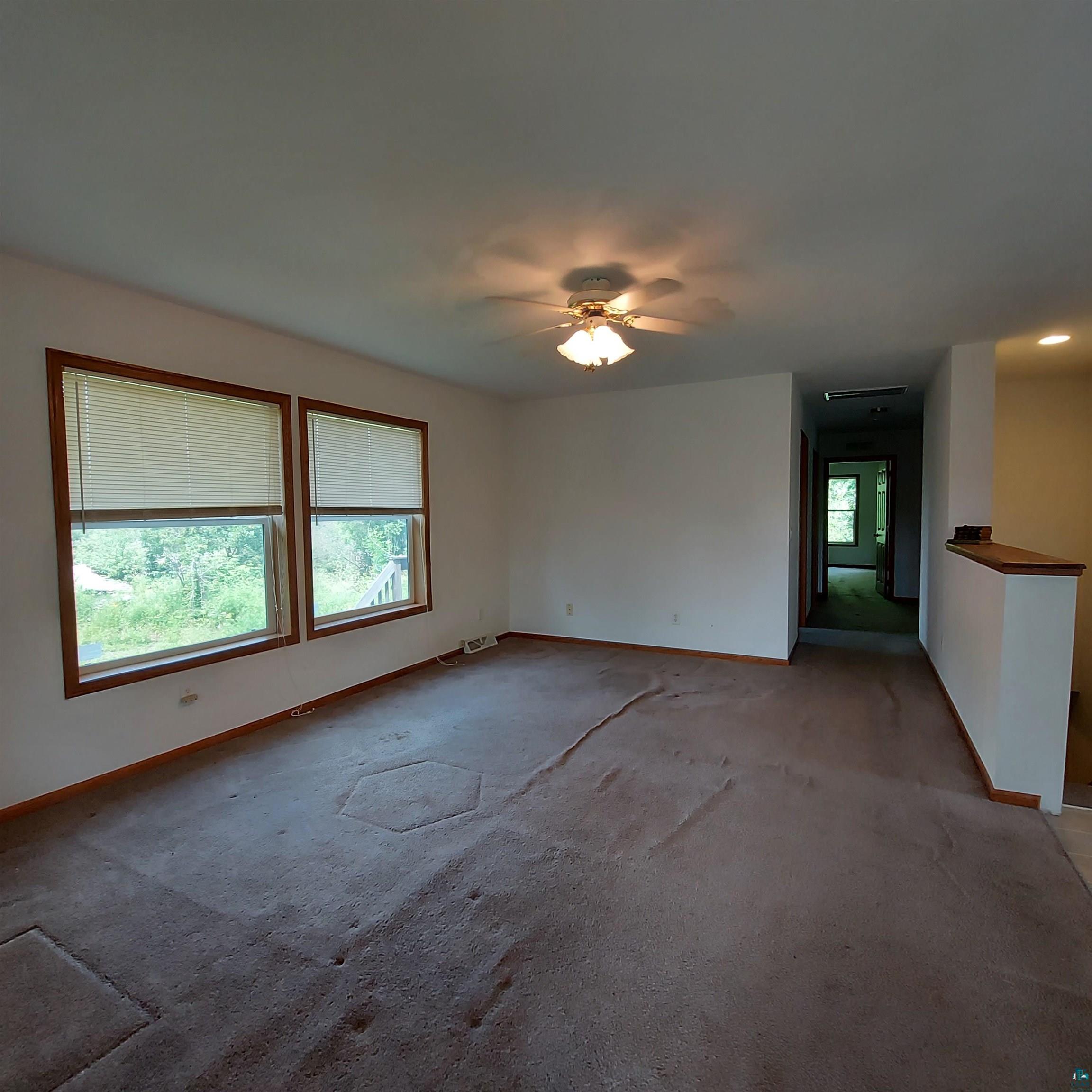 6563 Seville Road Saginaw, MN 55779 - Photo 8 of 28 Empty room with light carpet, ceiling fan, and a healthy amount of sunlight