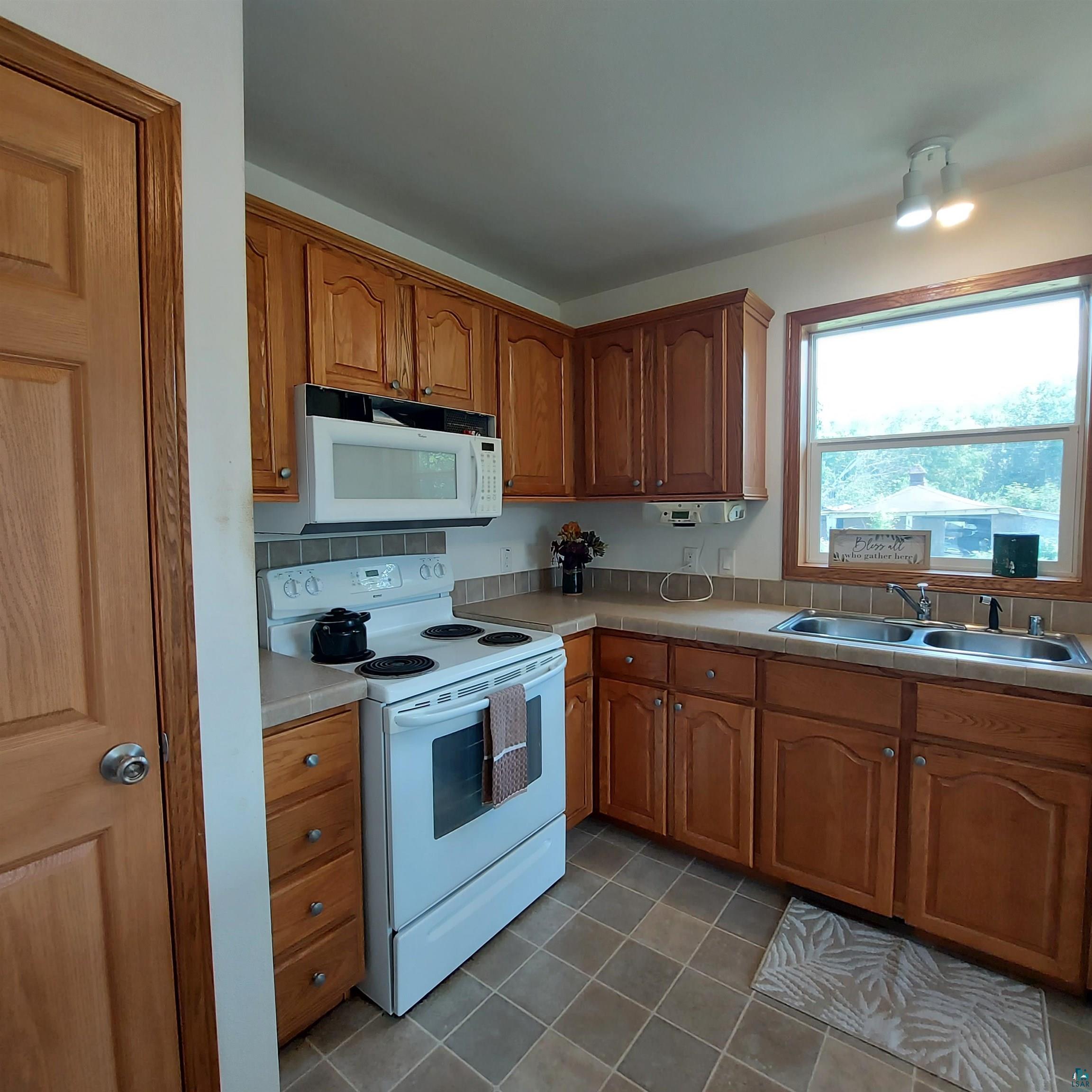 6563 Seville Road Saginaw, MN 55779 - Photo 10 of 28 Kitchen featuring tile patterned flooring, white appliances, and sink