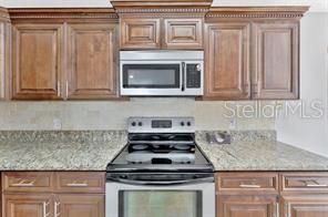1664 Portsmouth Lake Drive Brandon, FL 33511 - Photo 13 of 38 a kitchen with granite countertop stainless steel appliances stove top oven and cabinets