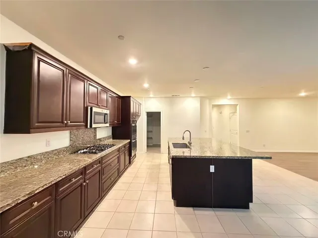 a large kitchen with kitchen island granite countertop a sink and cabinets
