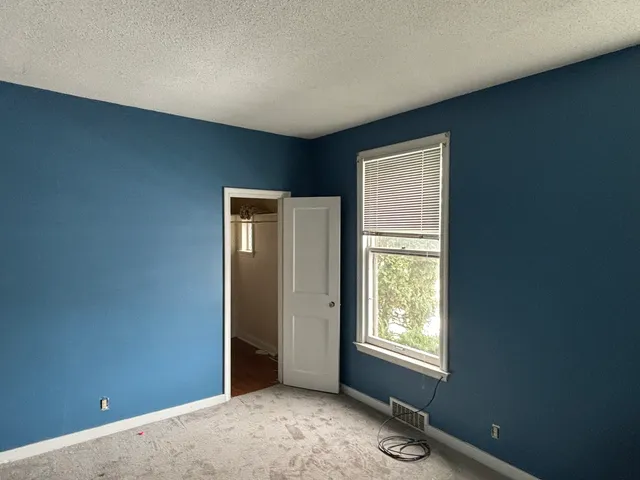 a view of an empty room with window and closet area