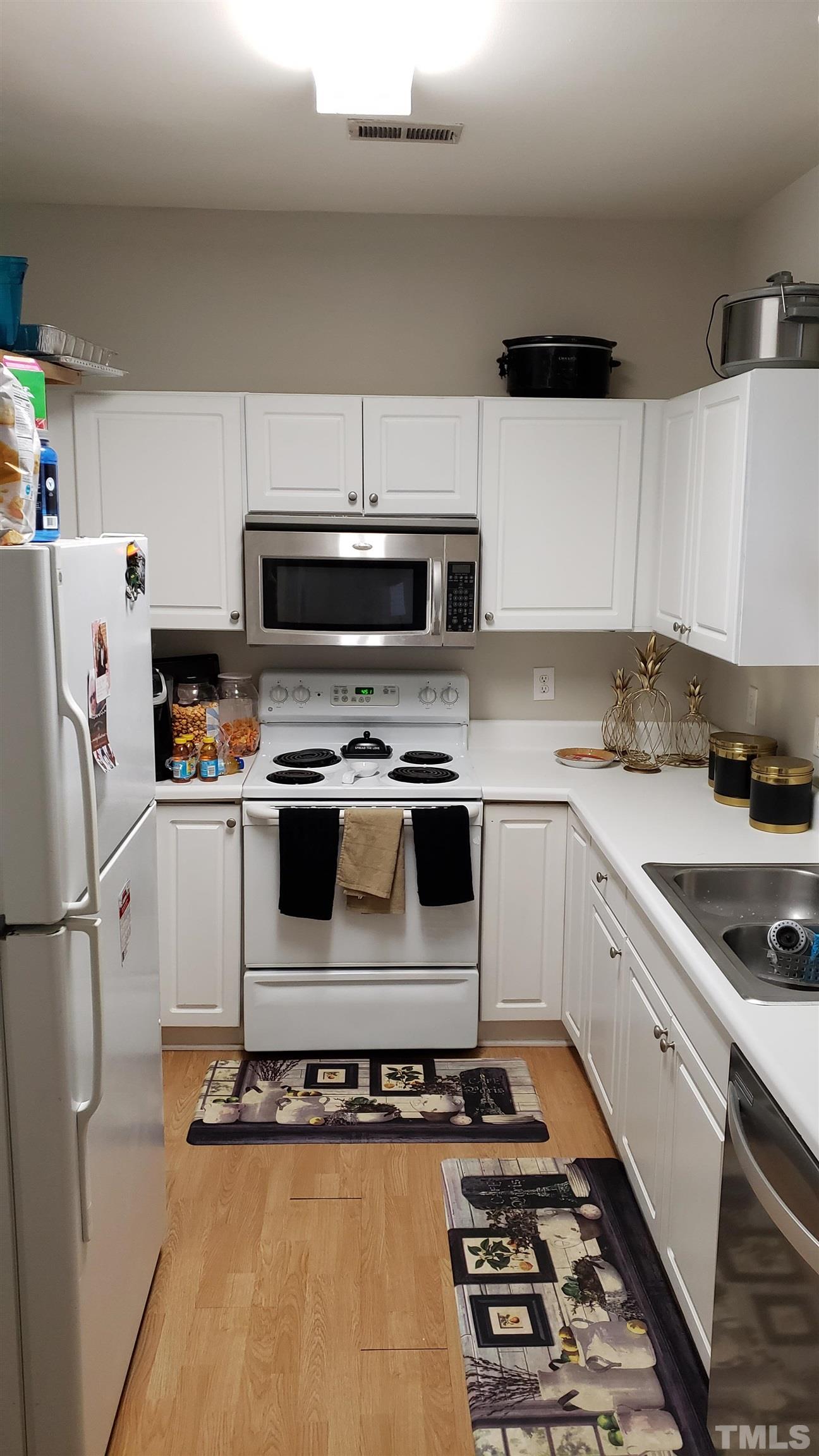 4125 Standing Rock Way Raleigh, NC 27604 - Photo 6 of 11 a kitchen with a refrigerator stove and white cabinets