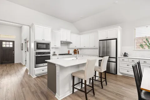 a kitchen with stainless steel appliances a microwave a stove a refrigerator a table and chairs