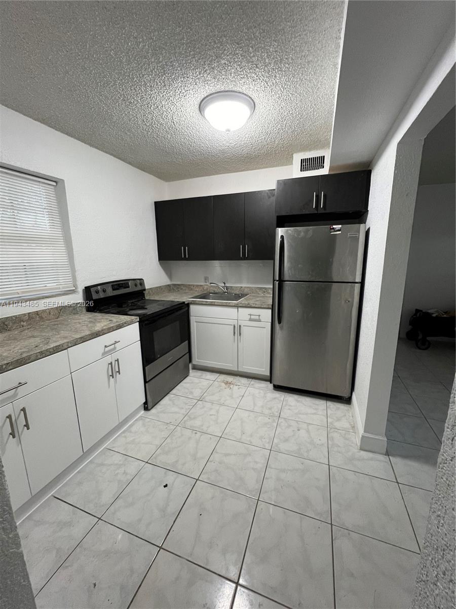 5819 Moseley Street Hollywood, FL 33021 - Photo 3 of 15 a kitchen with a refrigerator and a stove top oven