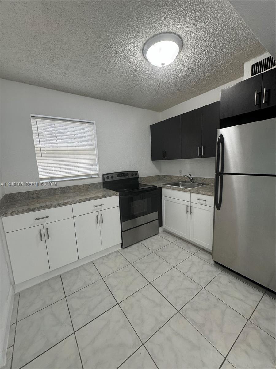 5819 Moseley Street Hollywood, FL 33021 - Photo 5 of 15 a kitchen with granite countertop a refrigerator sink and cabinets