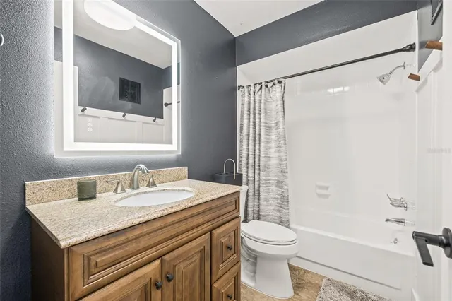 a bathroom with a granite countertop sink toilet and shower