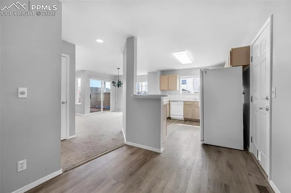 a view of a kitchen with refrigerator and wooden floor
