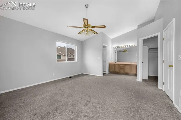 an empty room with chandelier fan and windows