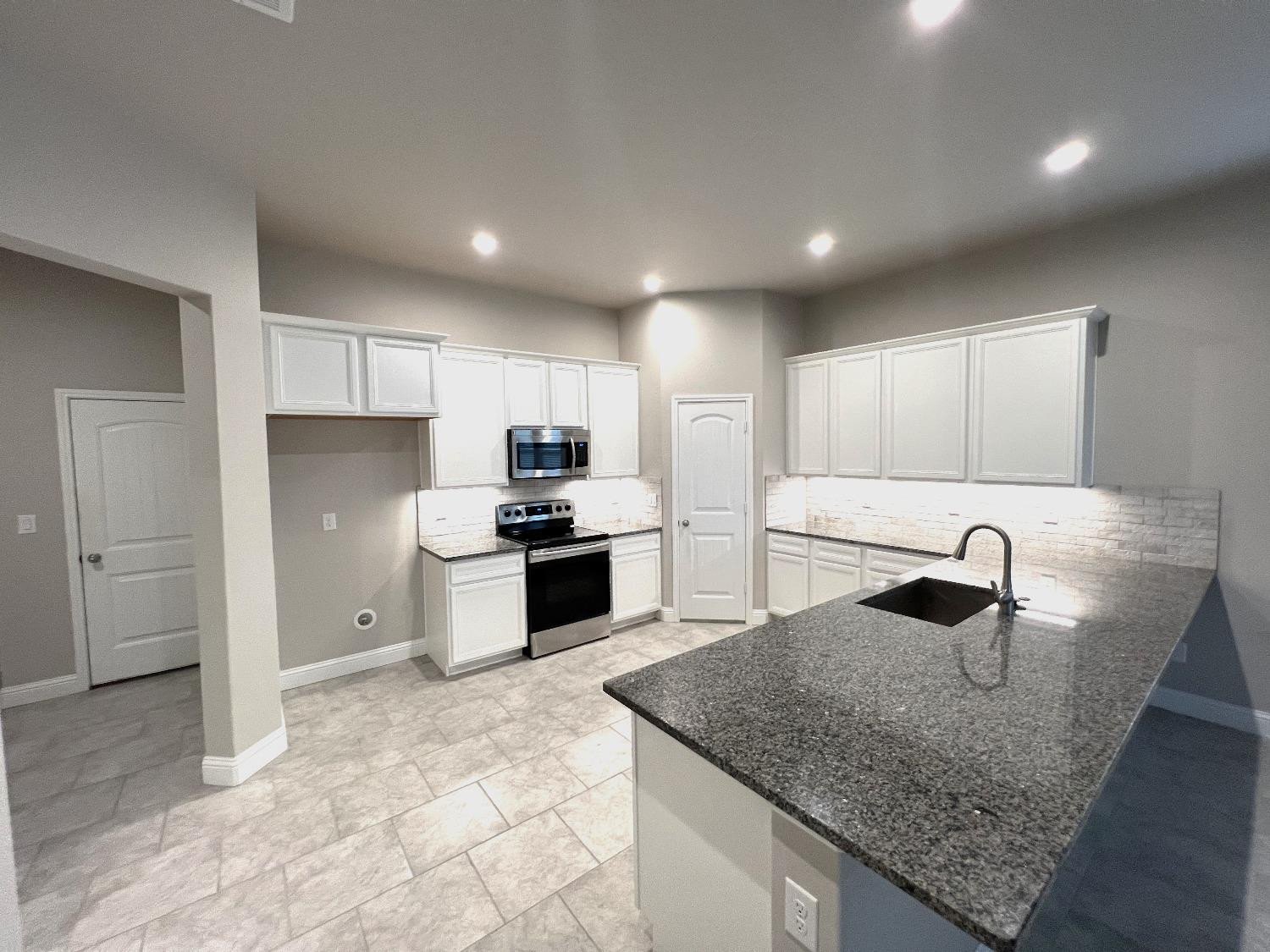 7506 100th Street Lubbock, TX 79424 - Photo 11 of 23 a kitchen with stainless steel appliances granite countertop a sink stove and refrigerator