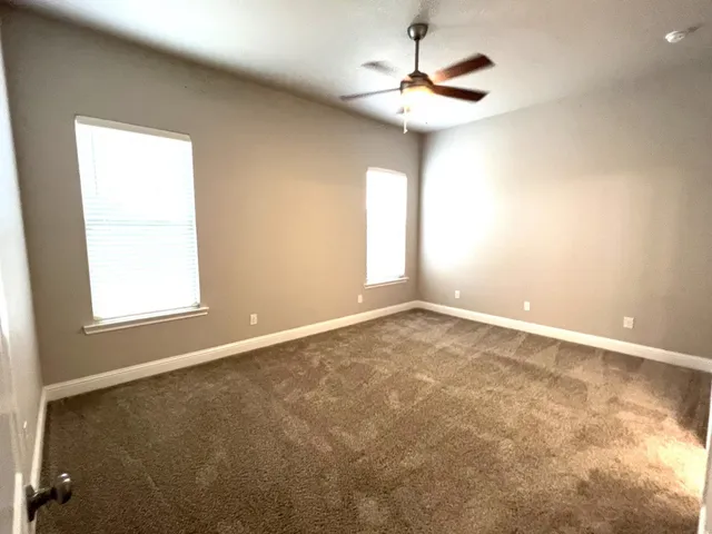 an empty room with a ceiling fan and window