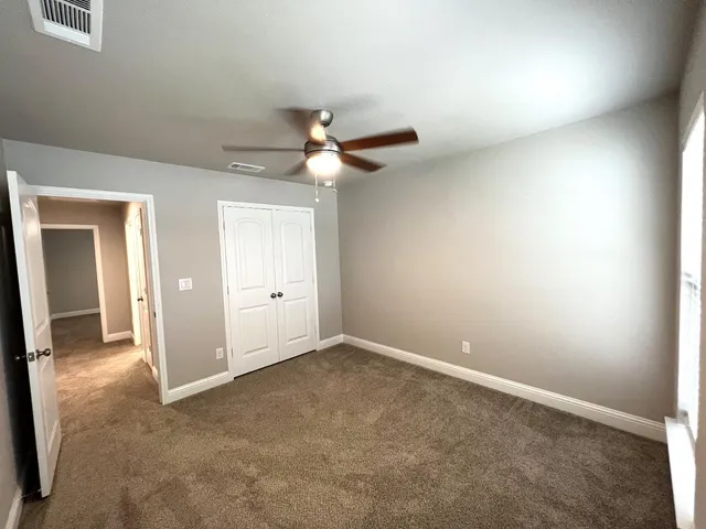 an empty room with a ceiling fan and a window