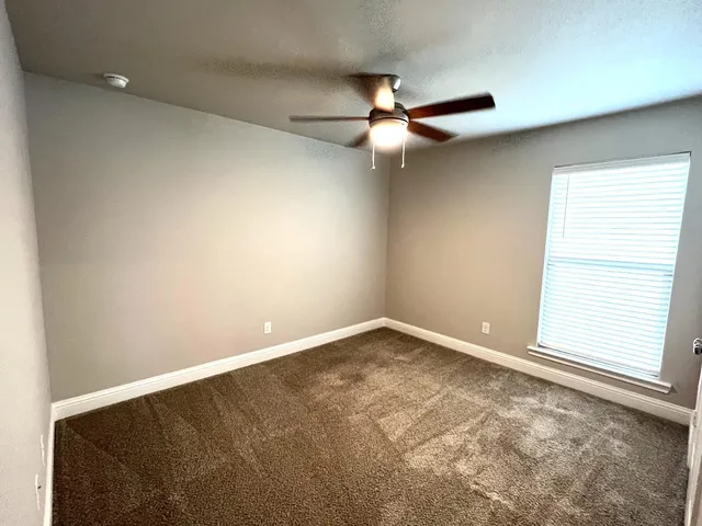 an empty room with a window and a fan