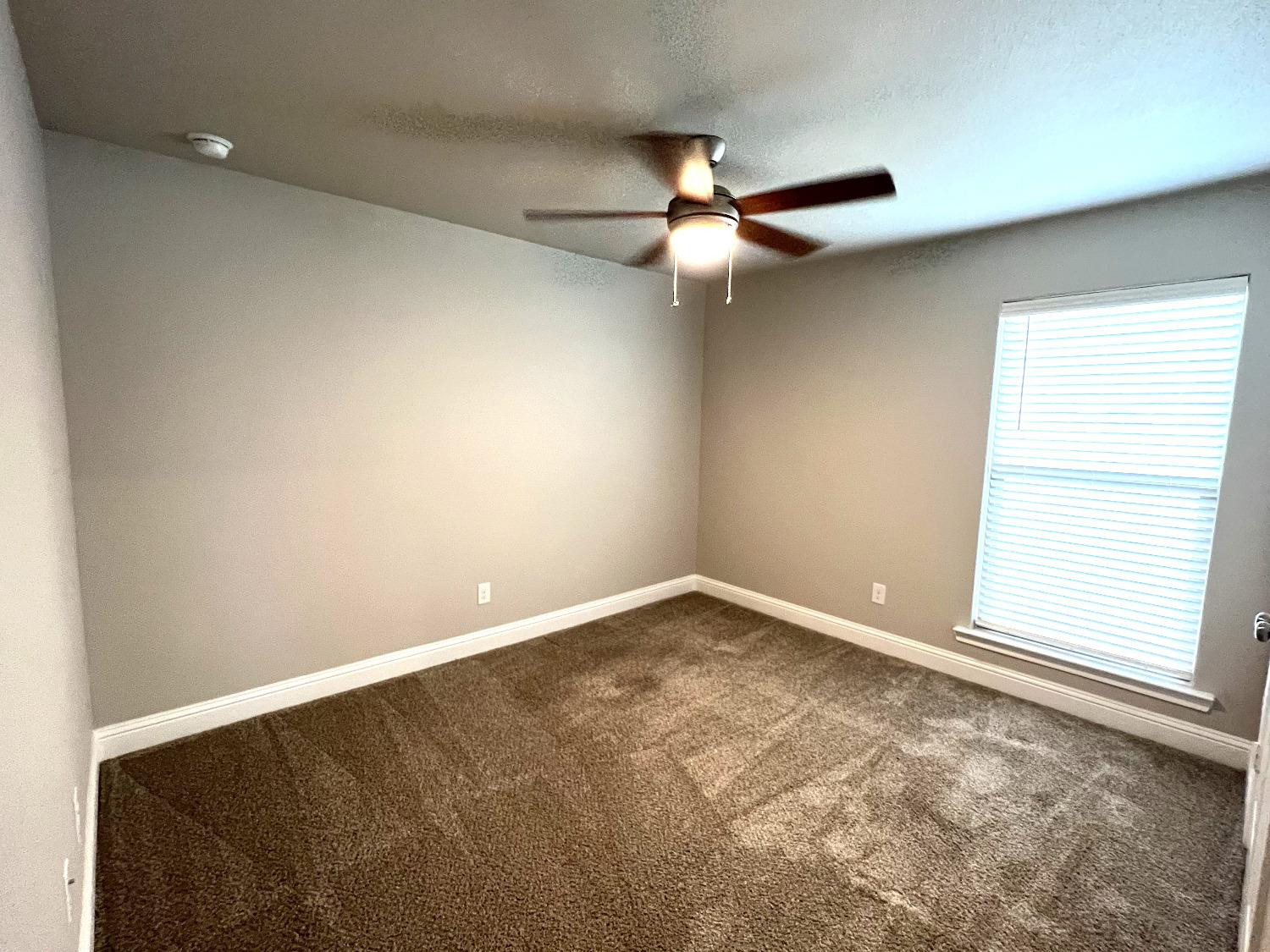 7506 100th Street Lubbock, TX 79424 - Photo 8 of 23 an empty room with a window and a fan