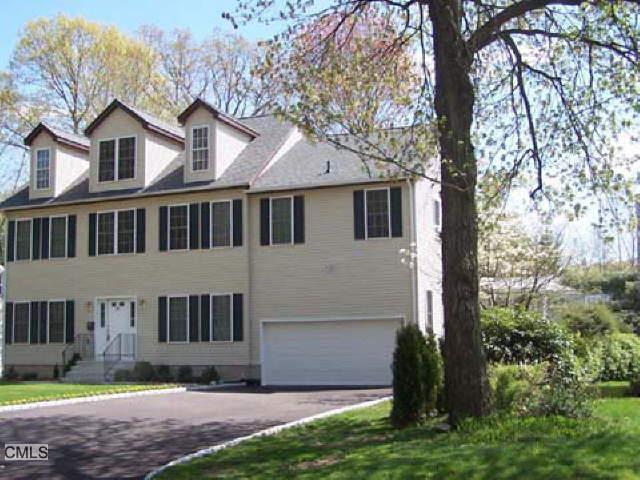 a view of a white house next to a yard with big trees
