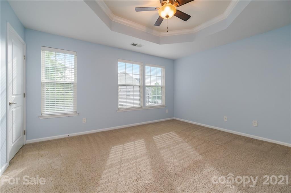 7304 Copper Beech Trace, Unit 13 Charlotte, NC 28273 - Photo 16 of 25 an empty room with a chandelier fan and windows