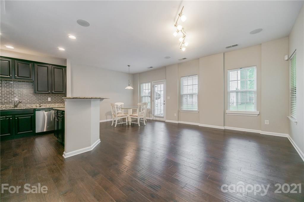 7304 Copper Beech Trace, Unit 13 Charlotte, NC 28273 - Photo 6 of 25 a kitchen with stainless steel appliances granite countertop a stove top oven a sink dishwasher a dining table and chairs with wooden floor