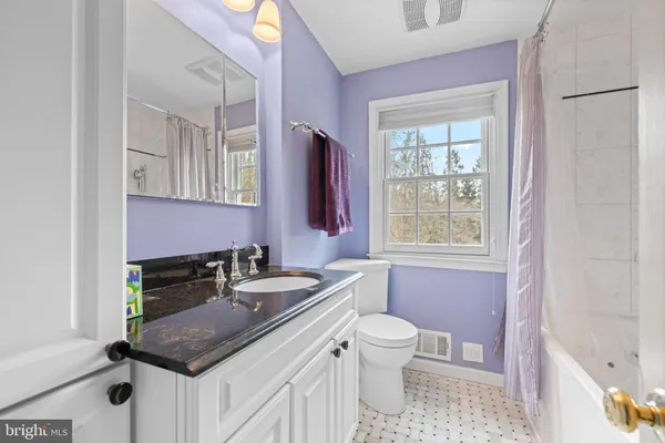 a bathroom with a granite countertop sink a toilet a mirror and window