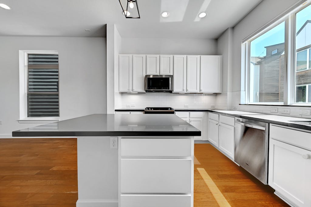 1412 Waterloo Shore Lane Austin, TX 78741 - Photo 11 of 30 a kitchen with granite countertop white cabinets and black stainless steel appliances
